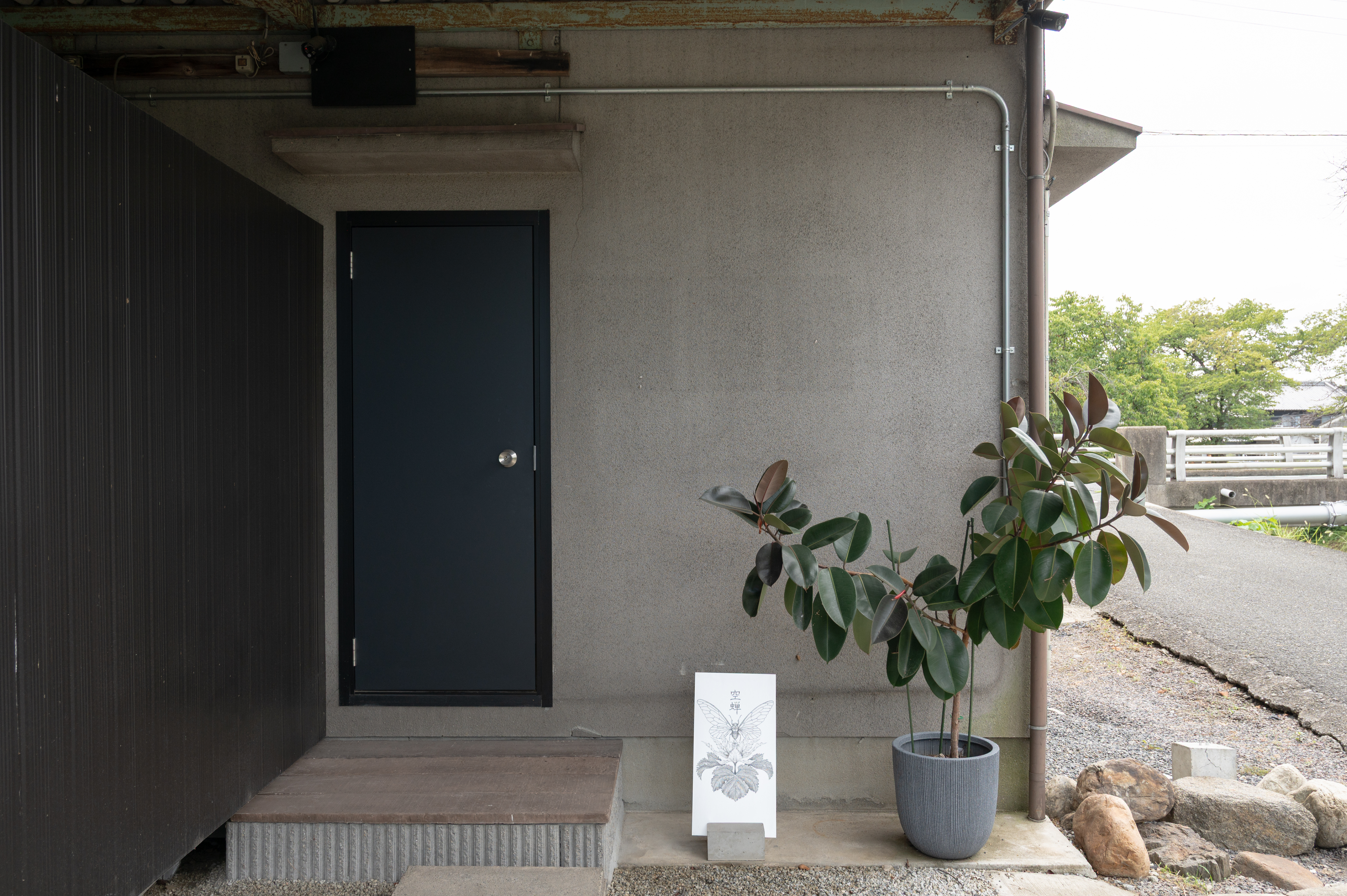 空蝉の店舗入口。黒い扉と空蝉の看板、鉢植えが目印
